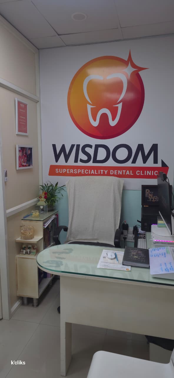 Consultation desk in front of the Wisdom Dental logo wall